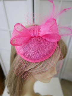 Różowy fascynator z sinamay z woalką i piórami na przepasce