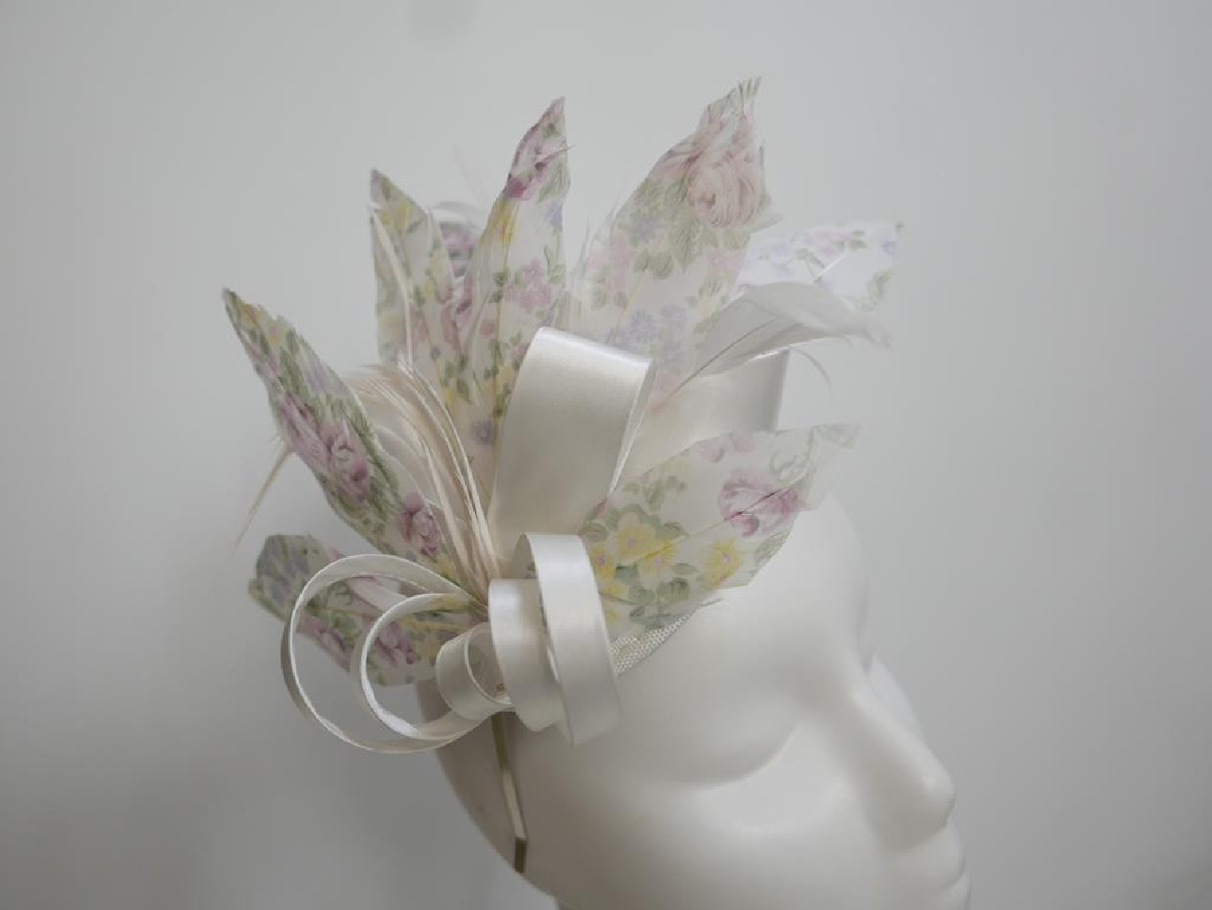 Pastelowy satynowy fascynator z piórami na przepasce
