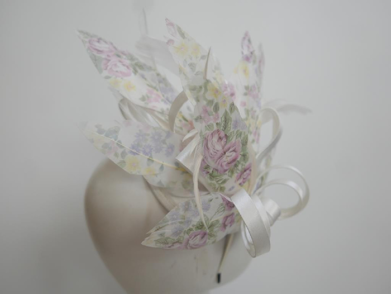 Pastelowy satynowy fascynator z piórami na przepasce