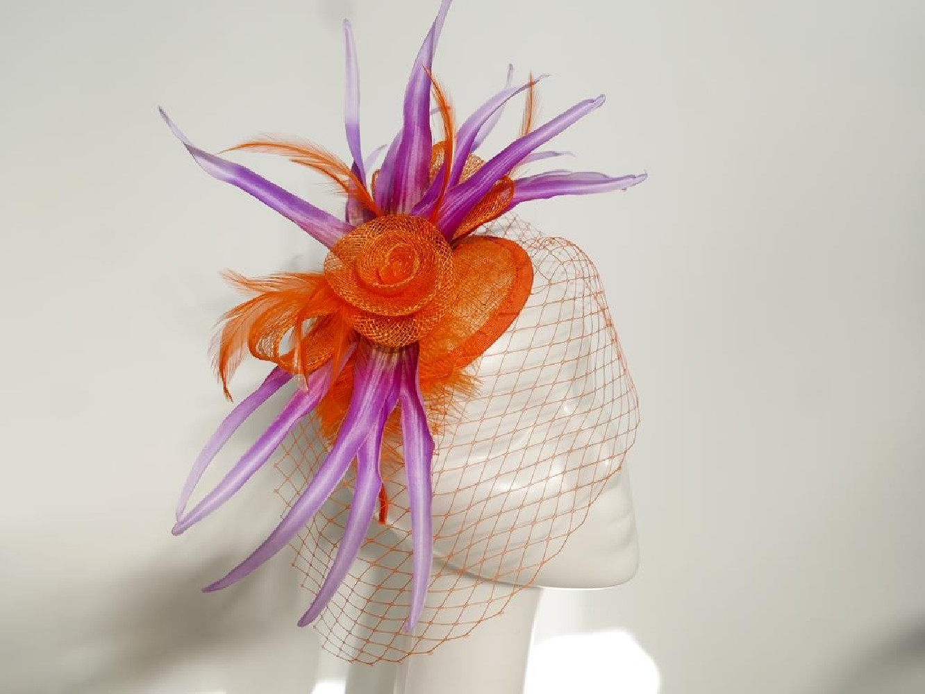 Pomarańczowo fioletowy fascynator z sinamay z woalką i piórami na przepasce