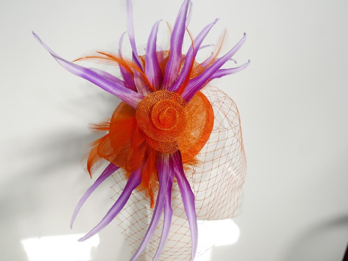 Pomarańczowo fioletowy fascynator z sinamay z woalką i piórami na przepasce