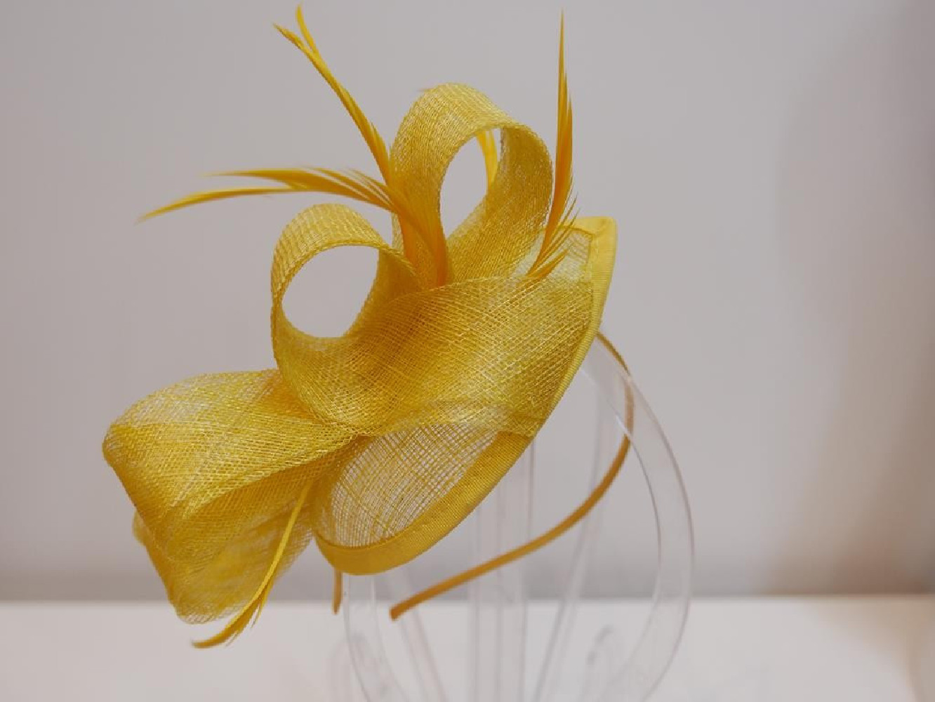 Żółty fascynator z sinamay z piórami na przepasce