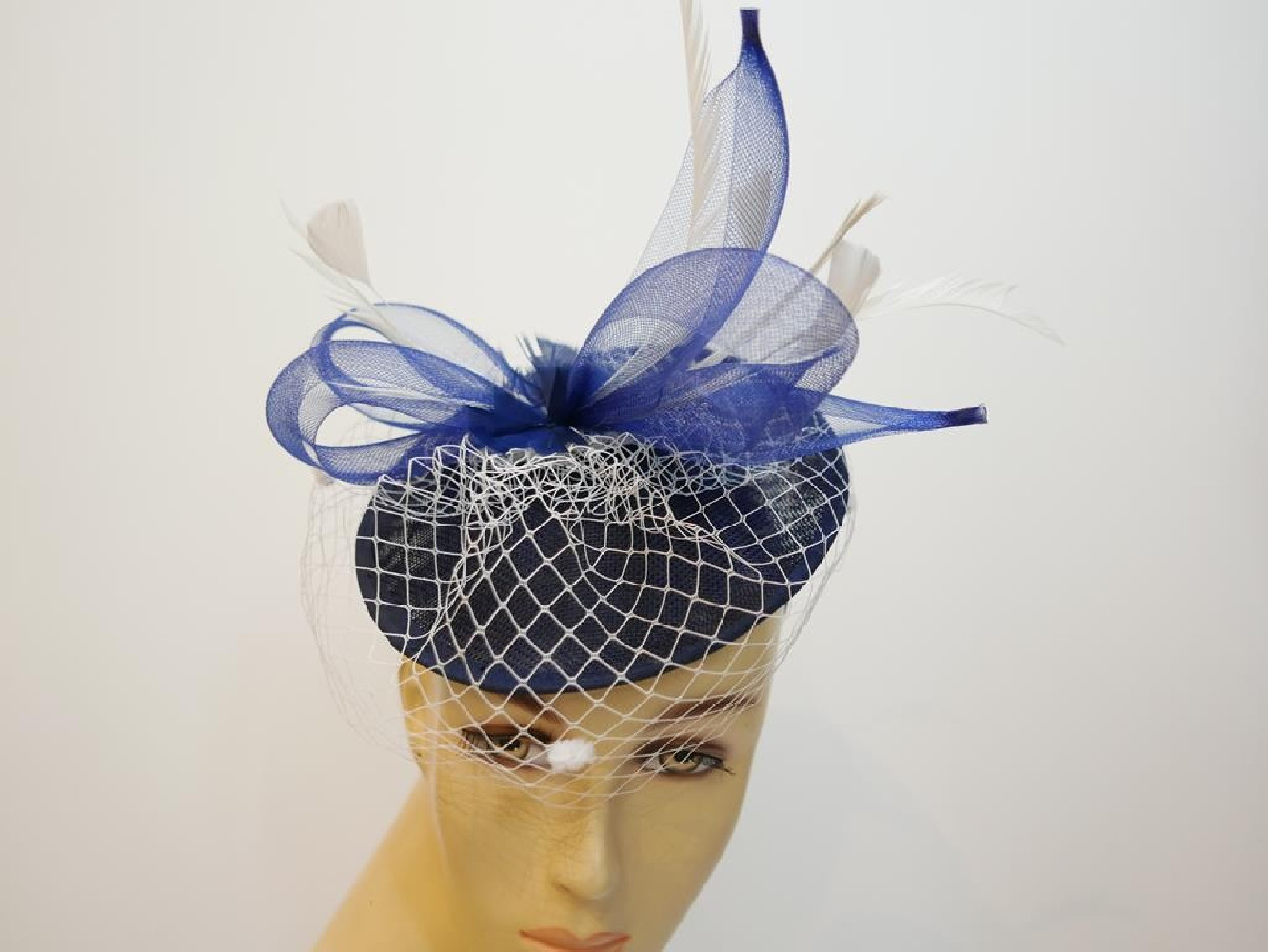 Granatowo śmietankowy fascynator z piórami i woalką na przepasce