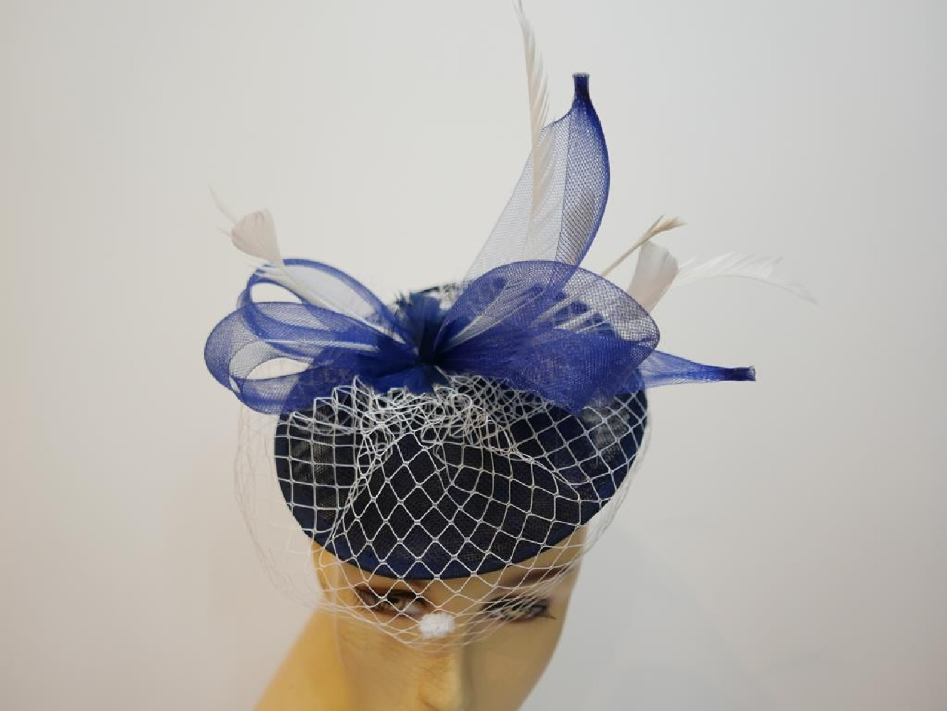 Granatowo śmietankowy fascynator z piórami i woalką na przepasce