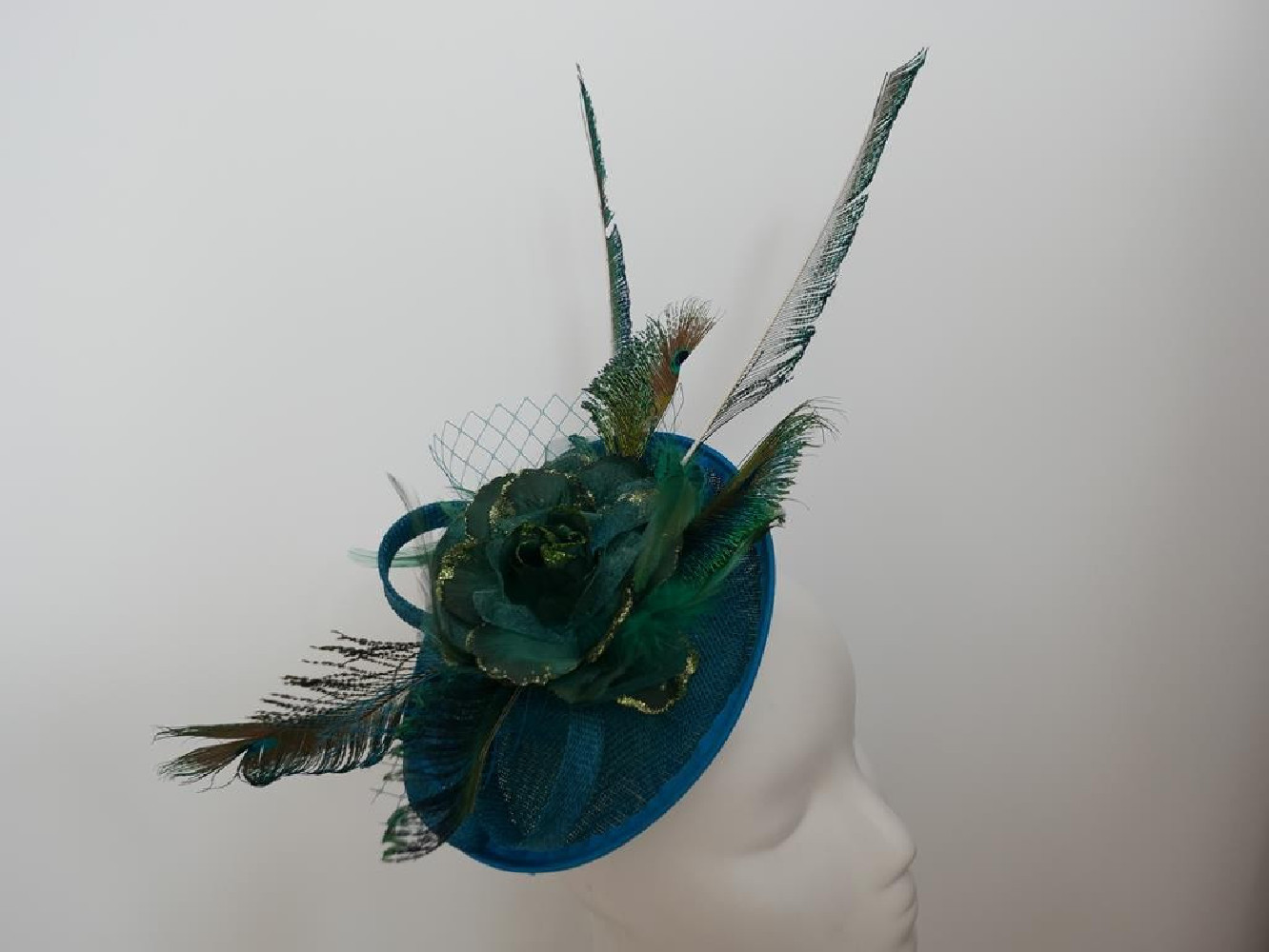 Turkusowo zielony fascynator z piórami i woalką na przepasce