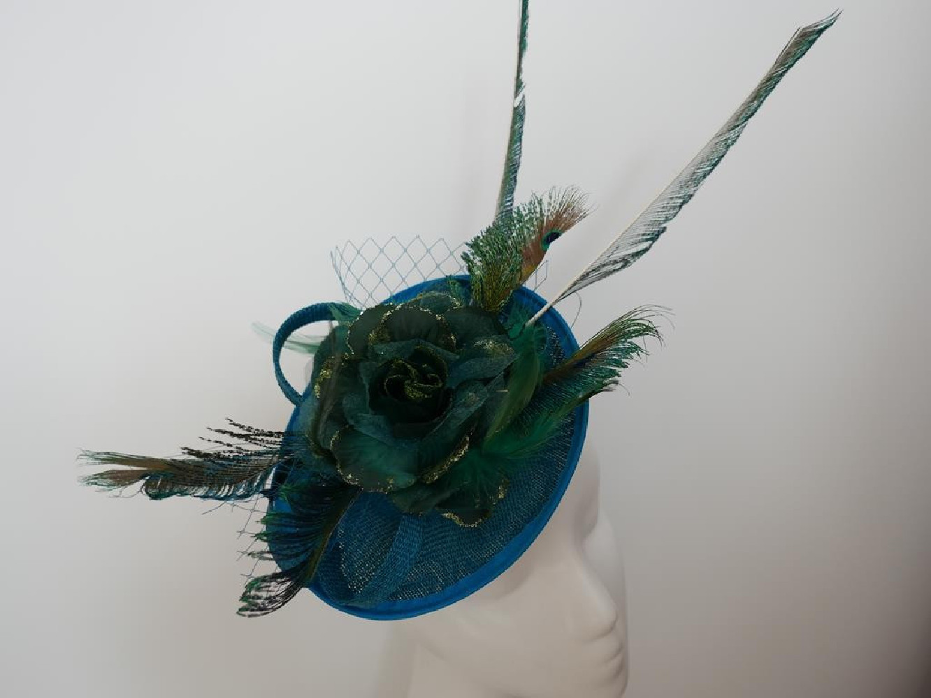 Turkusowo zielony fascynator z piórami i woalką na przepasce