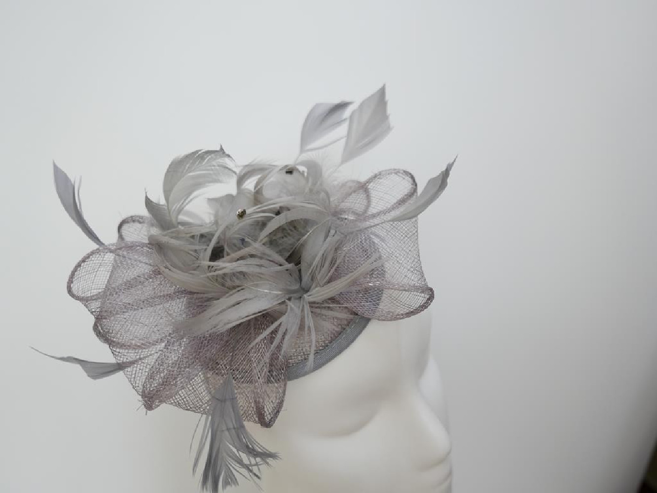 Szary fascynator z sinamay z piórami na przepasce