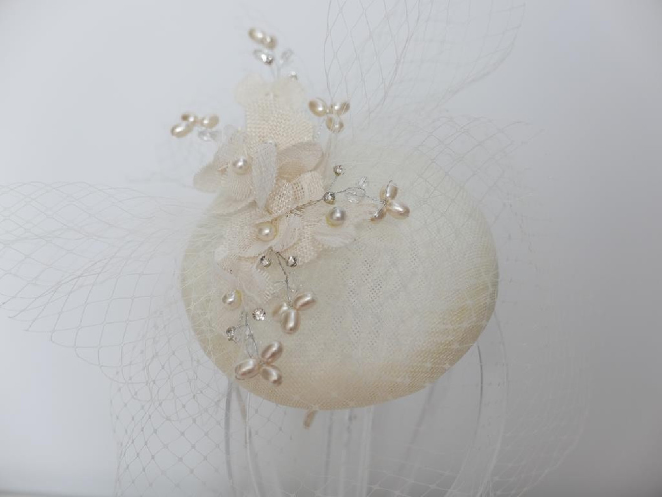Kremowy fascynator z lnu z kwiatami i woalką na przepasce