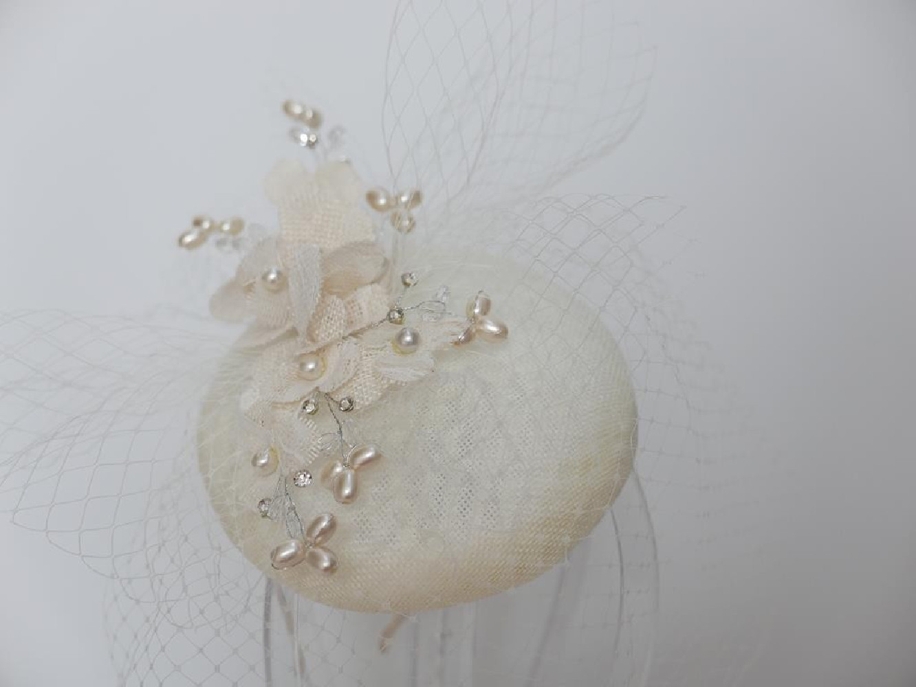 Kremowy fascynator z lnu z kwiatami i woalką na przepasce