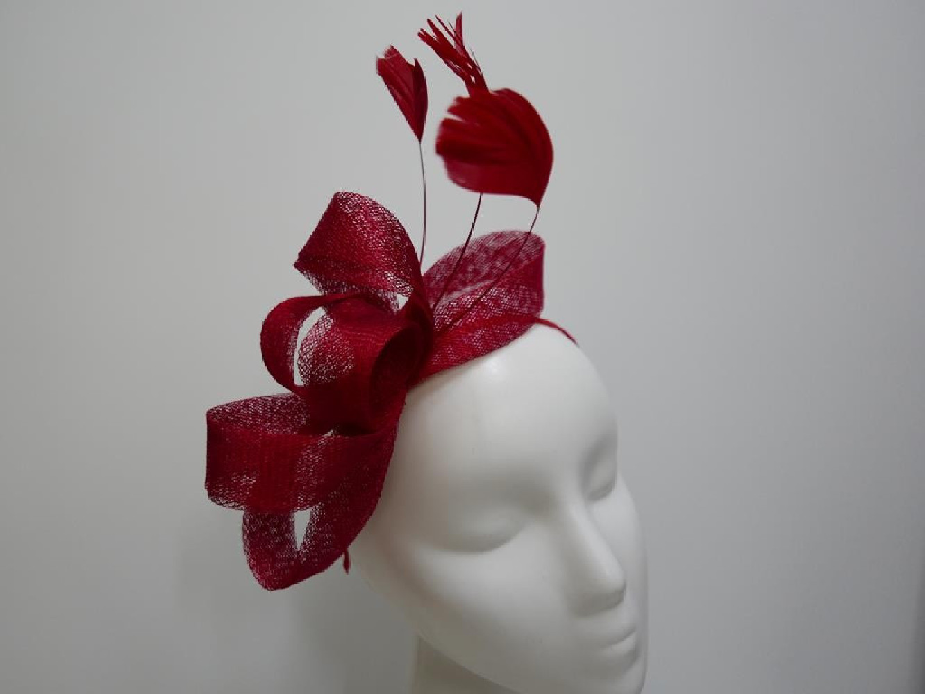 Czerwony fascynator z sinamay z piórami na przepasce