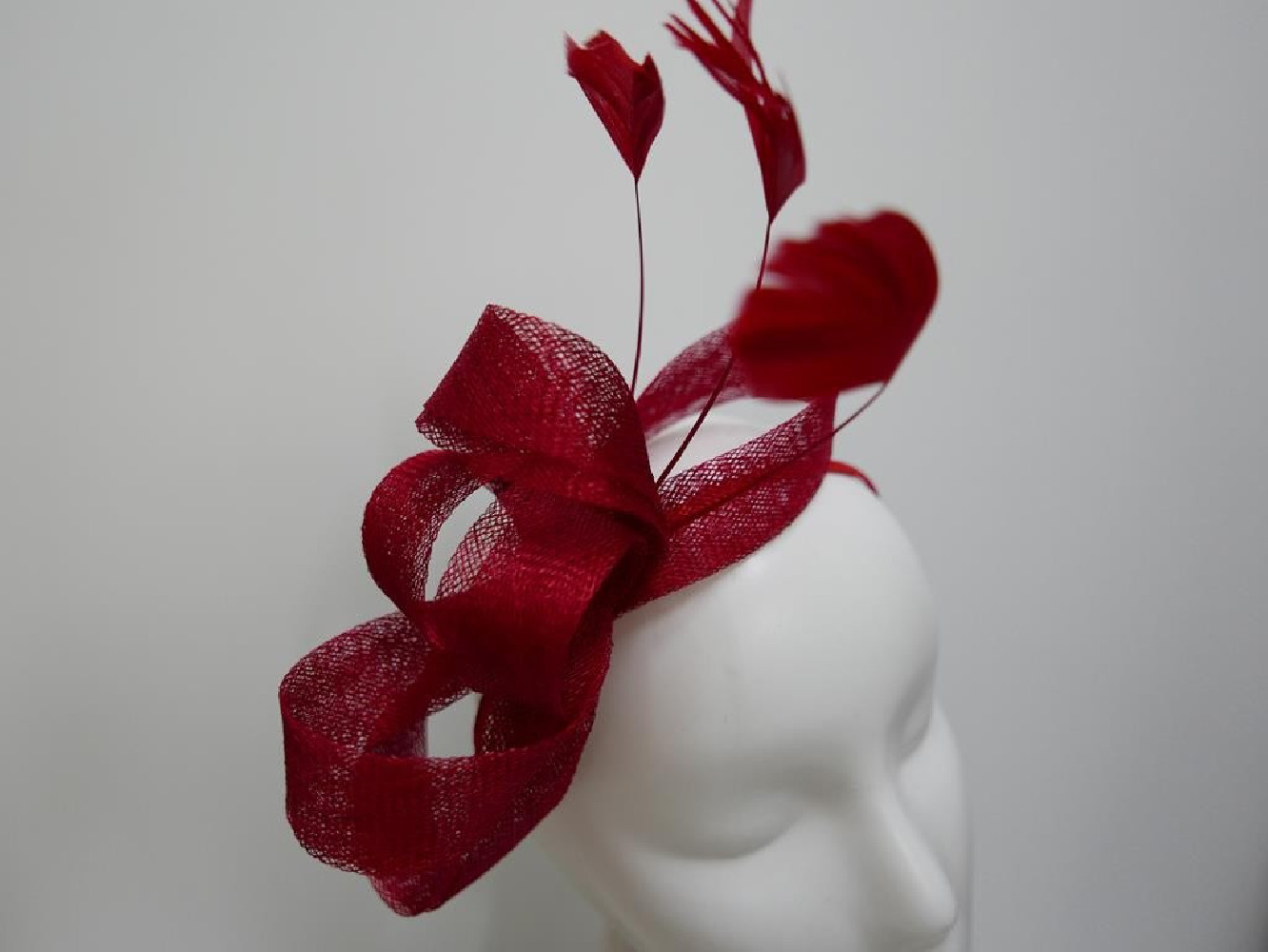 Czerwony fascynator z sinamay z piórami na przepasce