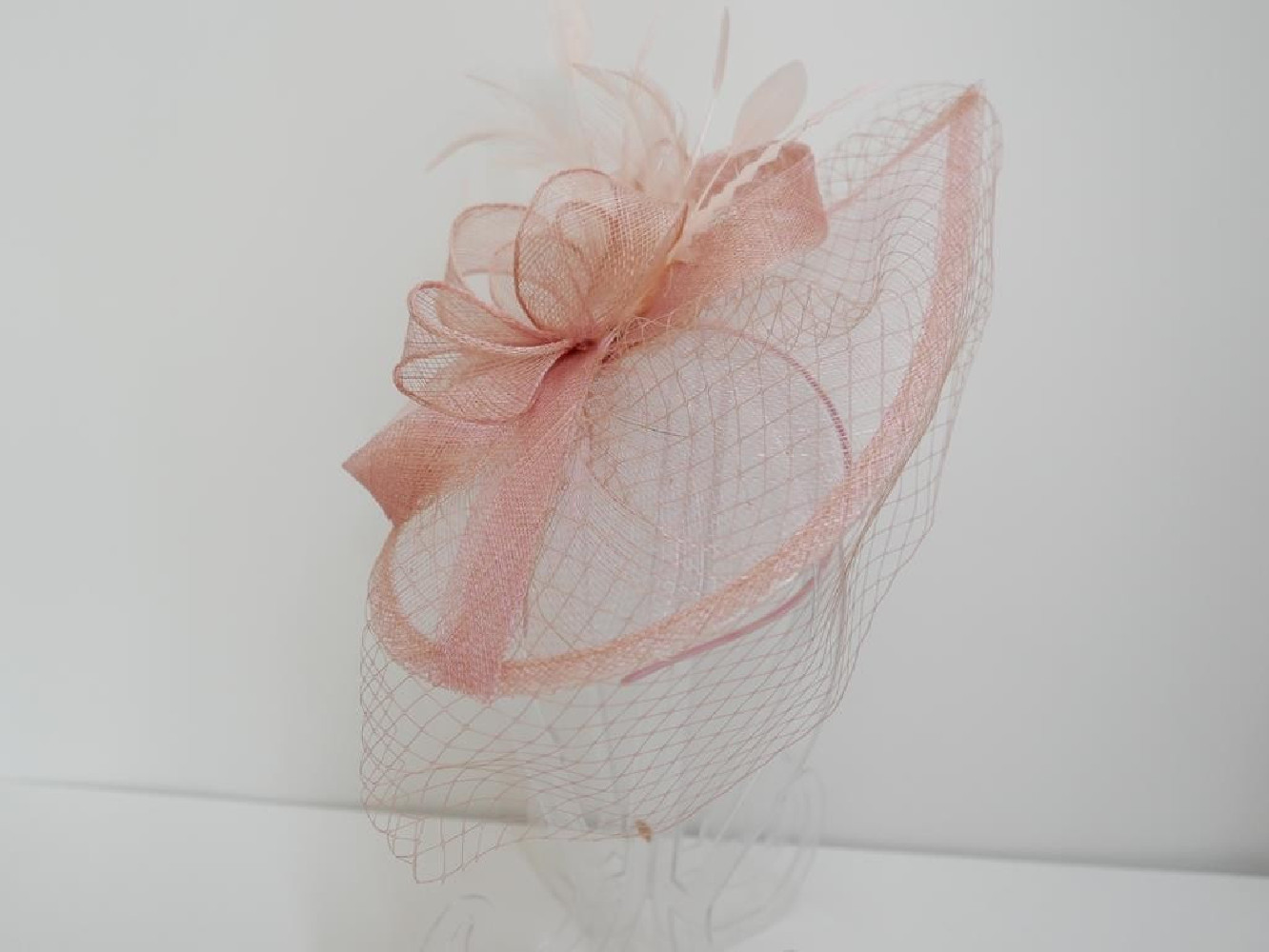 Różowy fascynator z sinamay z woalką na przepasce