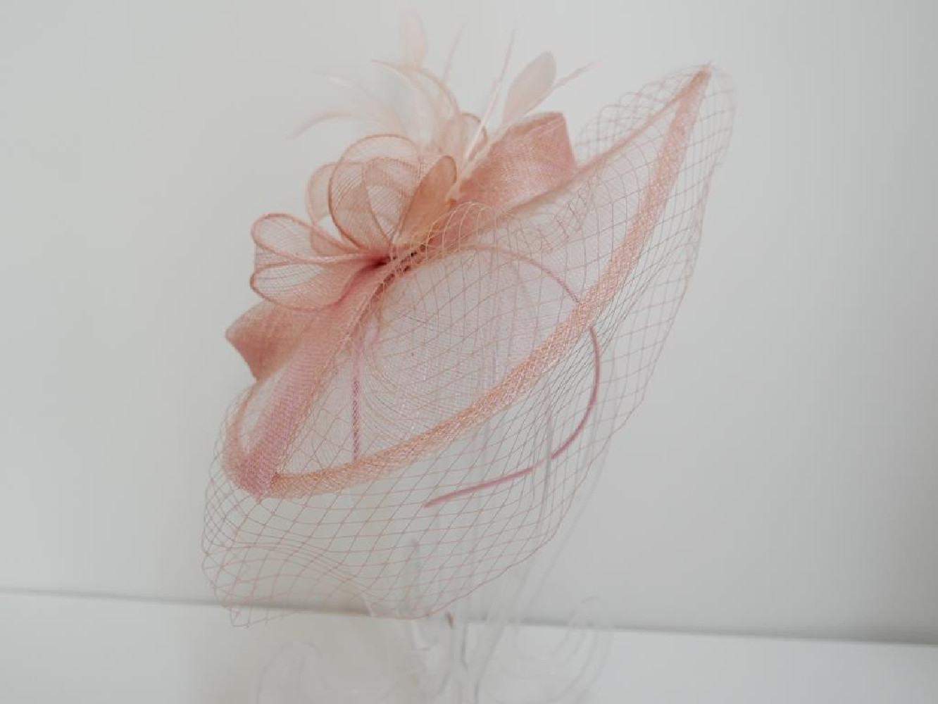 Różowy fascynator z sinamay z woalką na przepasce