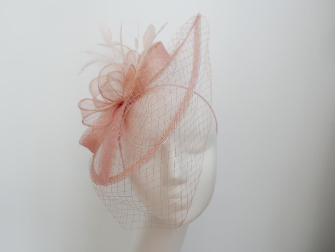 Różowy fascynator z sinamay z woalką na przepasce