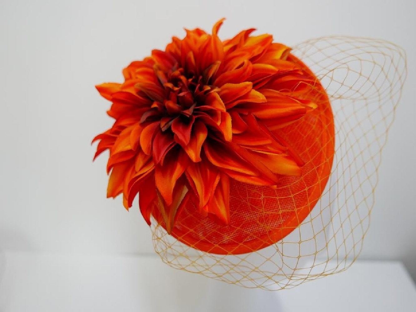 Pomarańczowy kapelusik koktajlowy  z lnu, kwiatami i woalką na przepasce