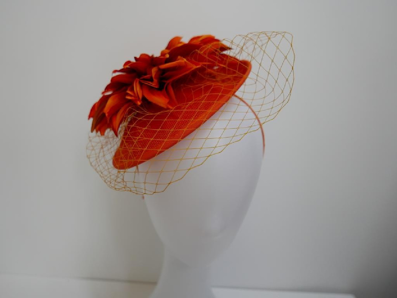 Pomarańczowy kapelusik koktajlowy  z lnu, kwiatami i woalką na przepasce