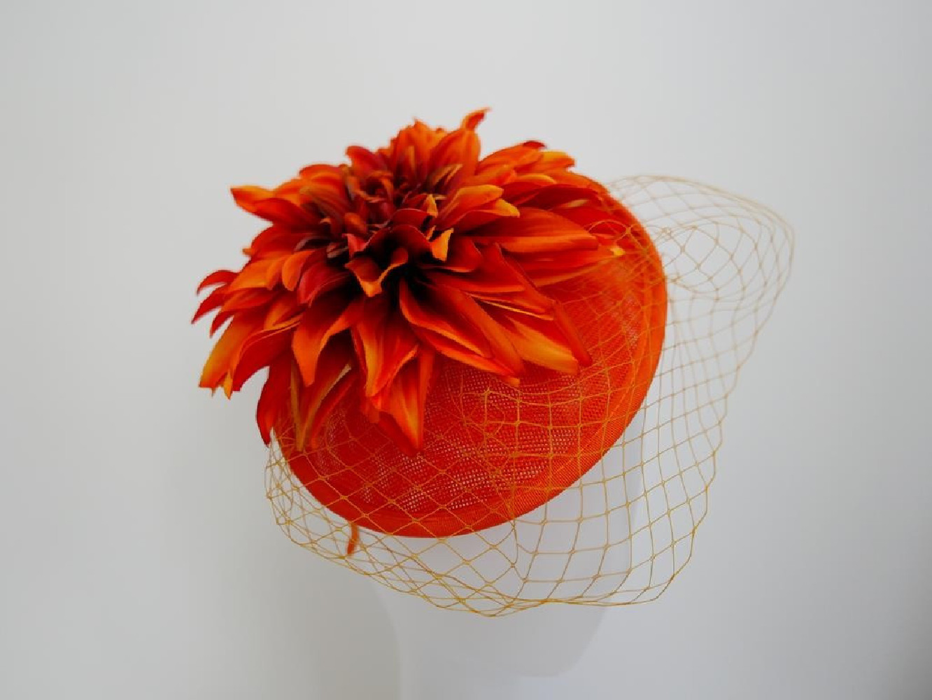 Pomarańczowy kapelusik koktajlowy  z lnu, kwiatami i woalką na przepasce