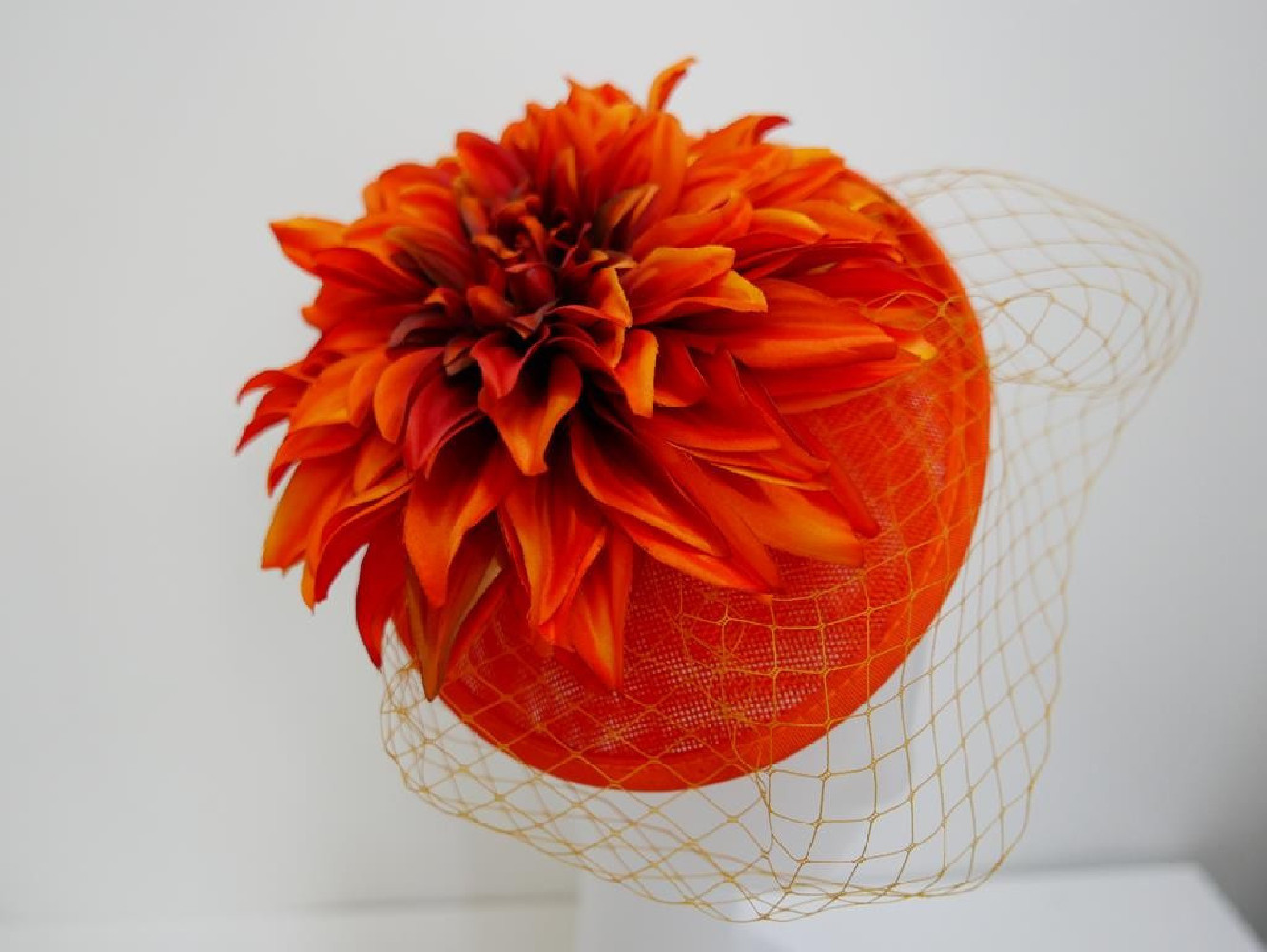 Pomarańczowy kapelusik koktajlowy  z lnu, kwiatami i woalką na przepasce