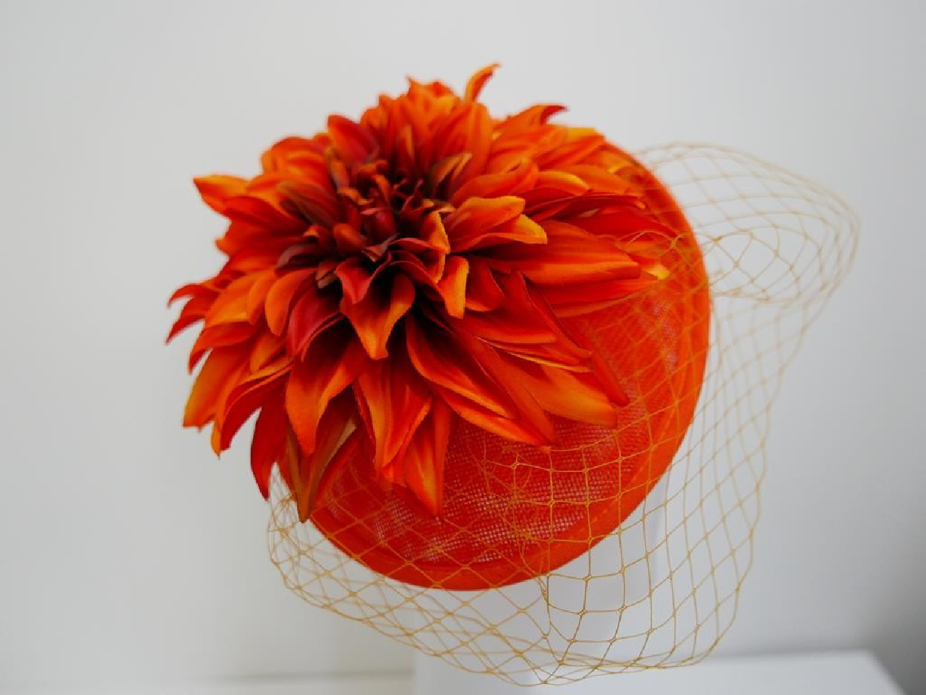 Pomarańczowy kapelusik koktajlowy  z lnu, kwiatami i woalką na przepasce