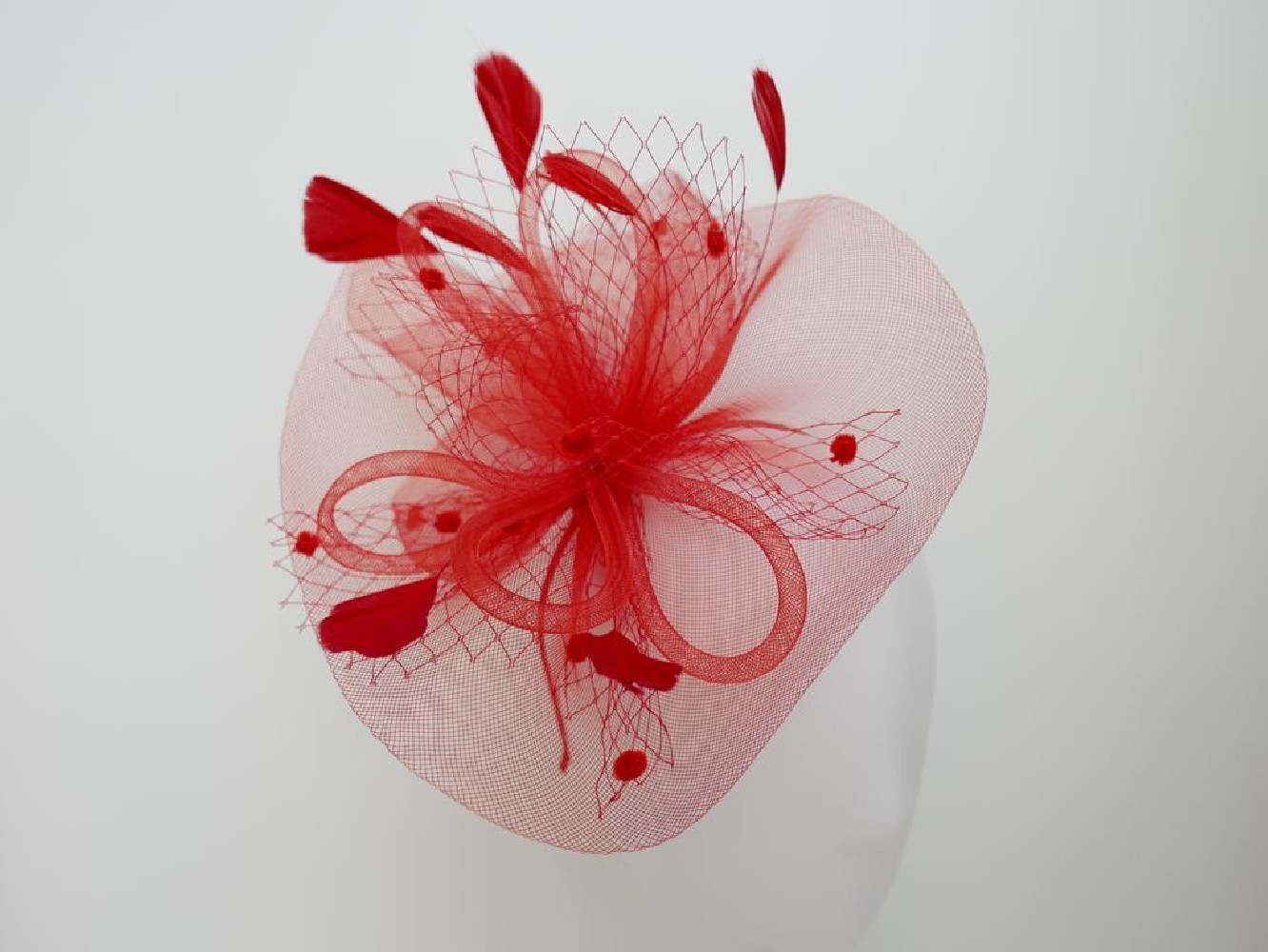 Czerwony fascynator z crin i piórami na przepasce