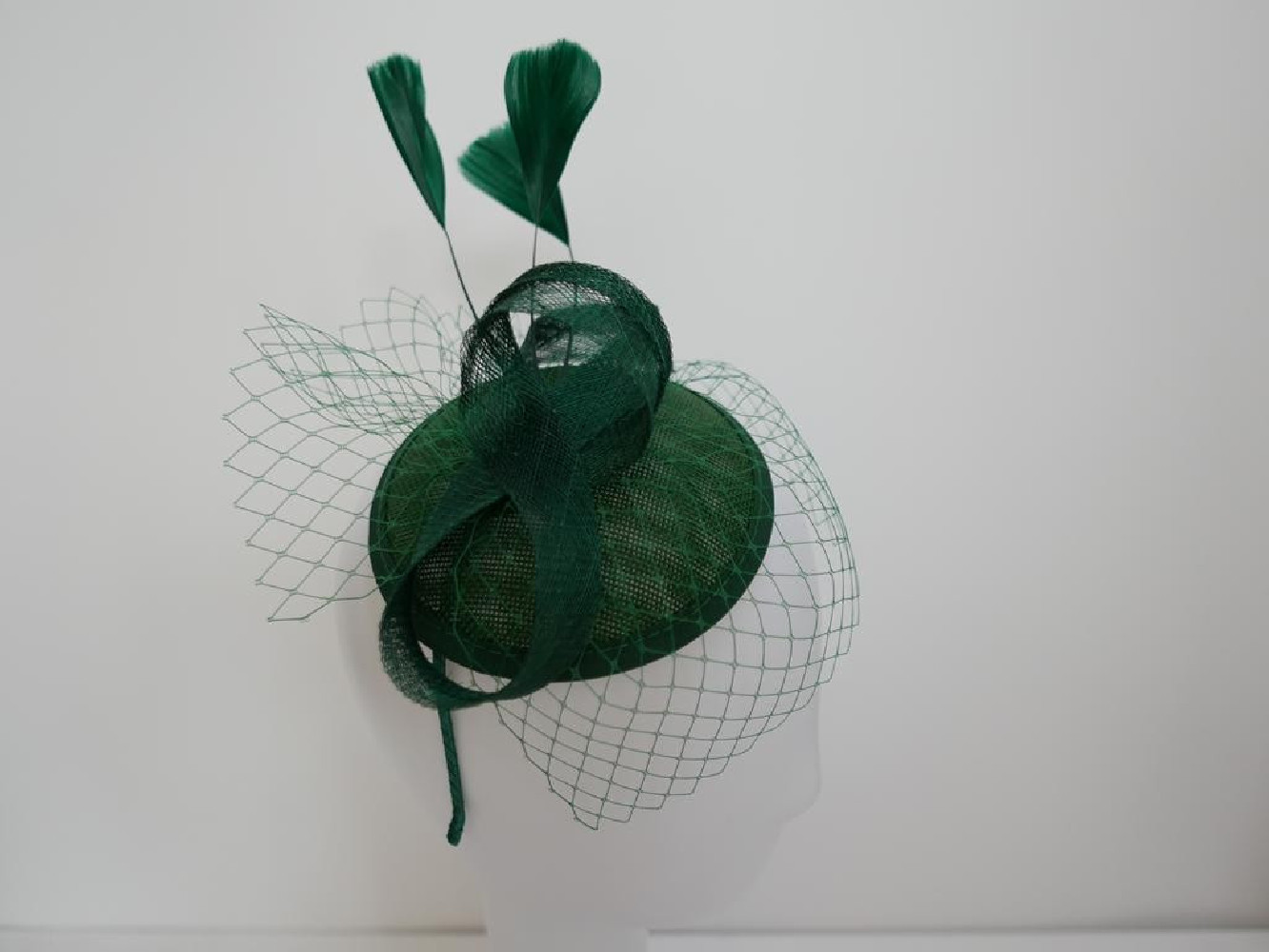 Zielony fascynator z woalką i piórami na przepasce
