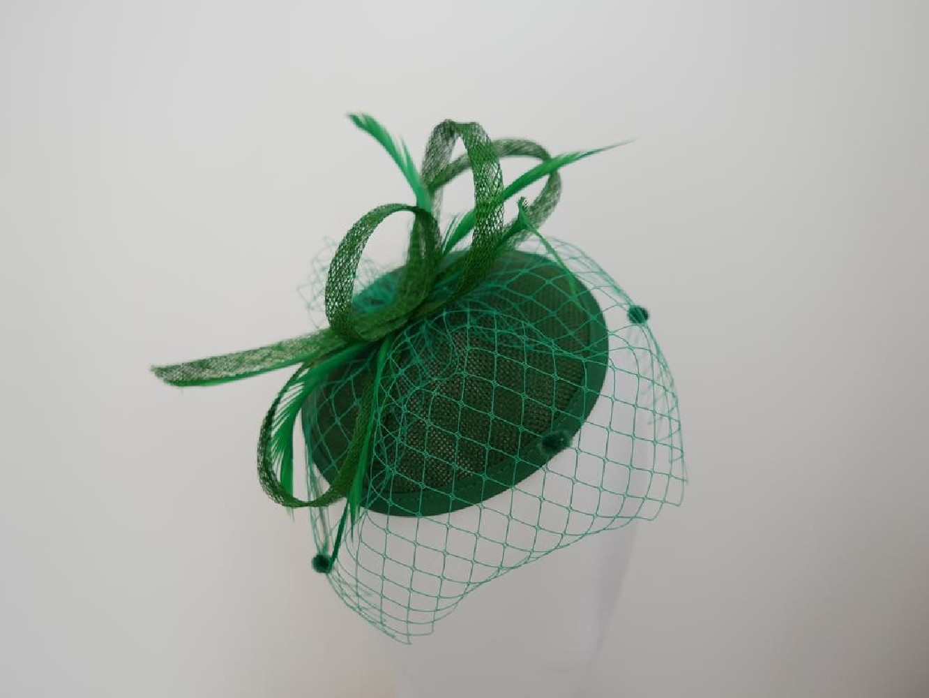 Zielony fascynator z woalką i piórami na przepasce