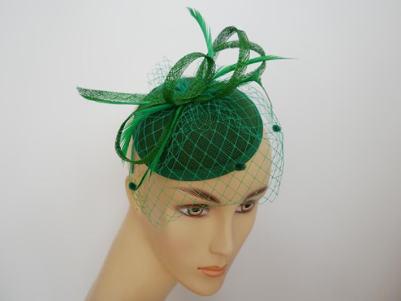 Zielony fascynator z woalką i piórami na przepasce