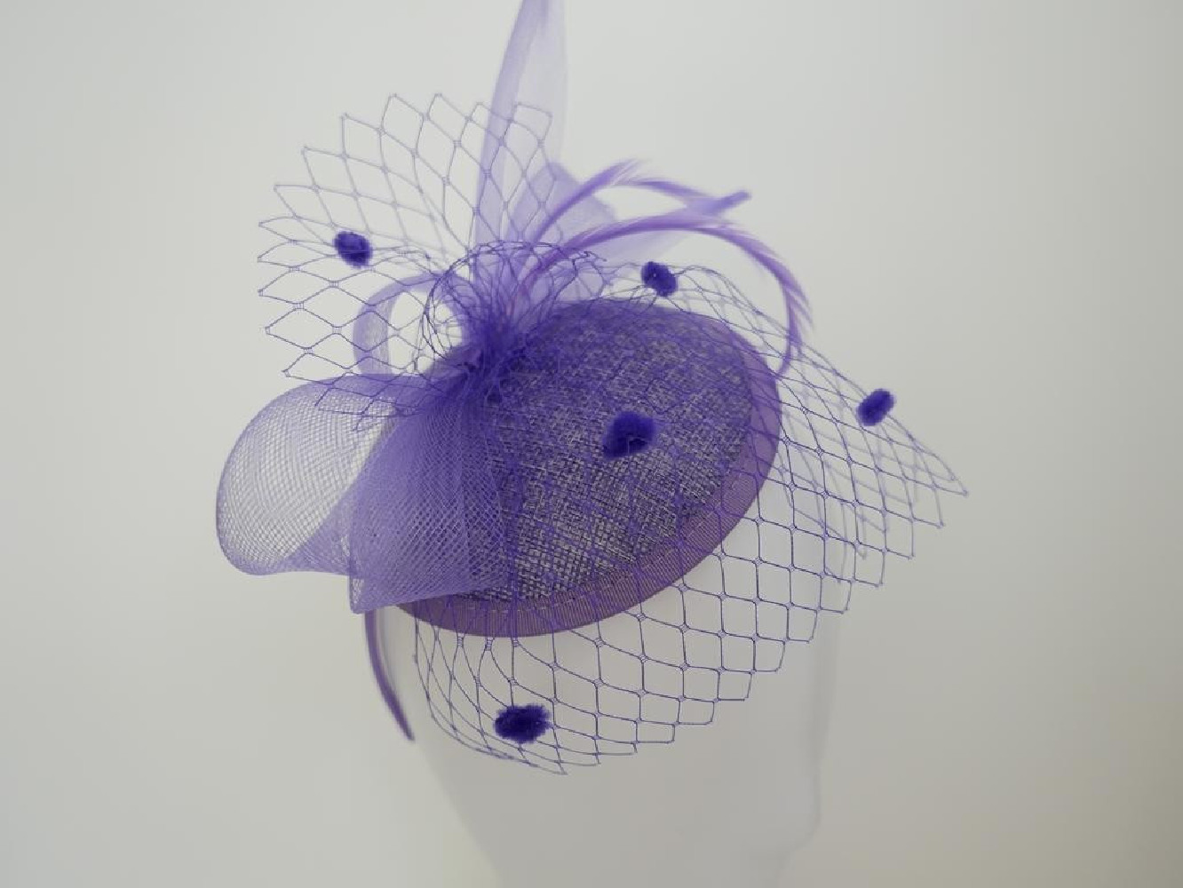 Liliowy fascynator z woalką i piórami na przepasce