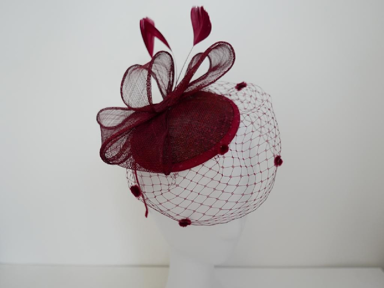 Bordowy fascynator z woalką i piórami na przepasce