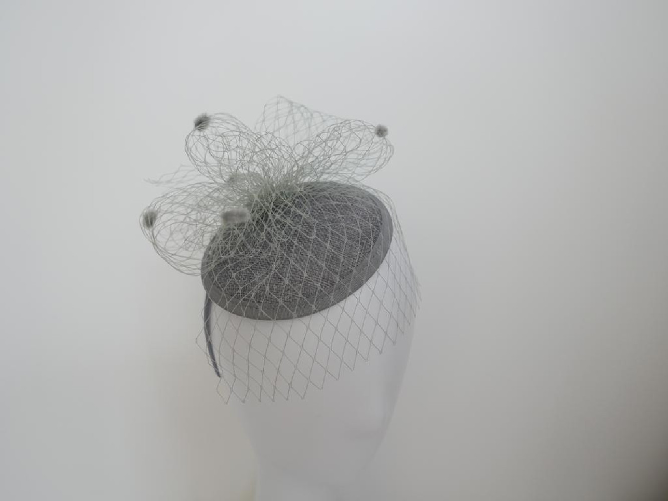Szary fascynator z woalką i piórami na przepasce