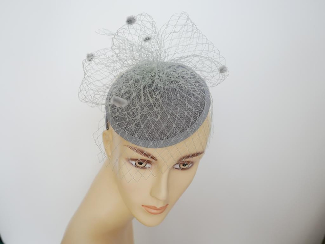 Szary fascynator z woalką i piórami na przepasce