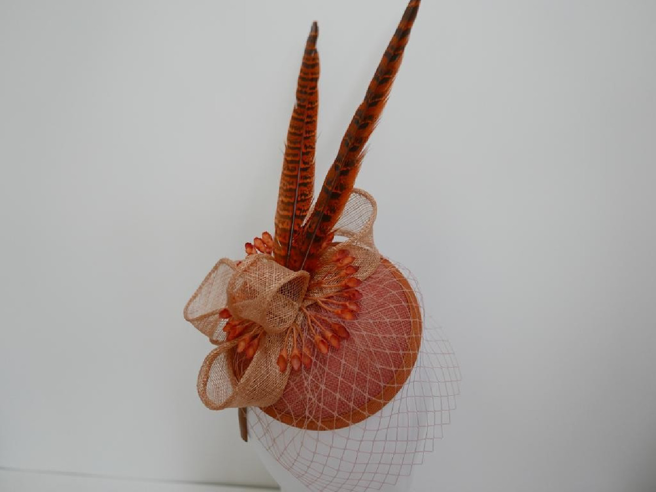 Koralowy fascynator z woalką i piórami na przepasce