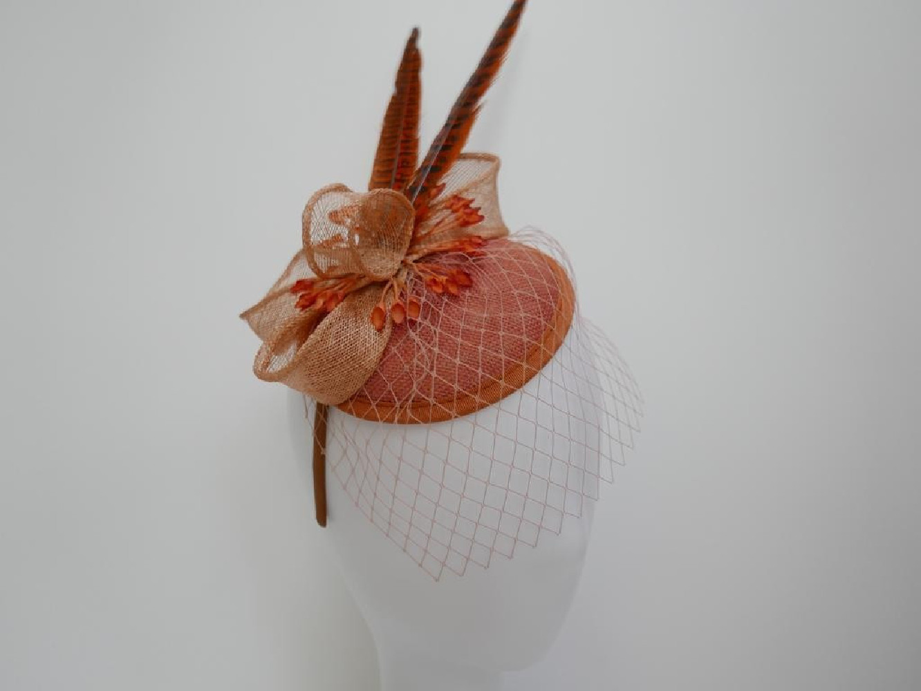 Koralowy fascynator z woalką i piórami na przepasce
