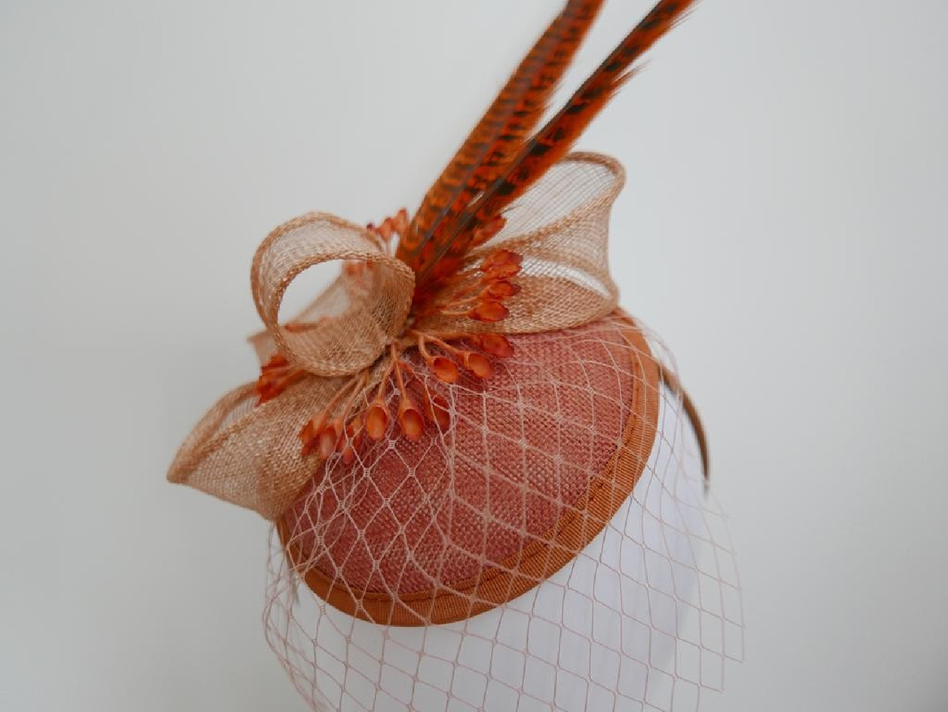 Koralowy fascynator z woalką i piórami na przepasce