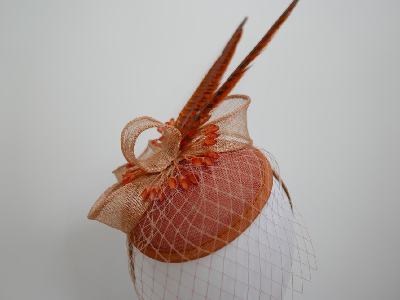 Koralowy fascynator z woalką i piórami na przepasce