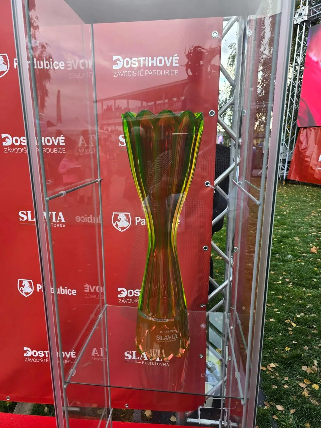 Szklany puchar Wielkiej Pardubickiej w gablocie przy ściance wydarzenia.